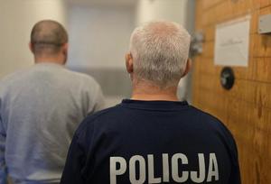 na zdjeciu zatrzymany z policjantem stoją tyłem