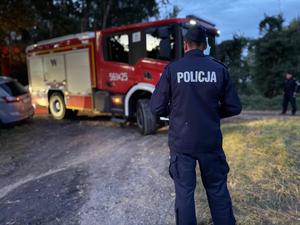 na zdjeciu policjant a przed nim pojazd straży pożarnej