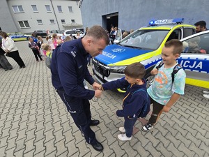 na zdjęciu komendant pokazuje dzieciom kajdanki