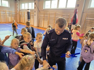 na zdjeciu komendant zakłada dzieciom odblaski