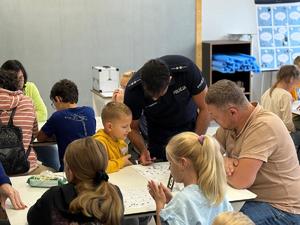 na zdjęciu policjant pokazuje jak zrobić odcisk palca