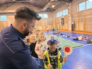 na zdjęciu policjant ubiera kamizelkę chłopczykowi