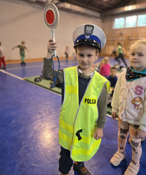 na zdjęciu chłopczyk w kamizelce i czapce policyjnej trzyma tarcze