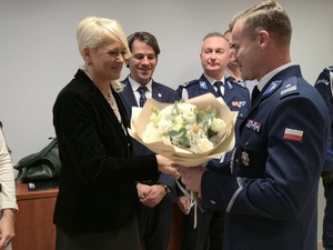 na zdjęciu komendant daje kwiaty sekretarce