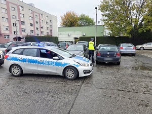 na zdjęciu policjant podczas kontroli volkswagena obok stoi radiowóz
