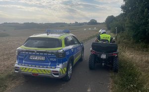 na zdjęciu policjant na quadzie i radiowóz obok kontrolują tereny leśne