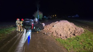 NA ZDJECIU POJAZD KTÓRY DACHOWAŁ A OBOK STOJĄ STRAŻACY