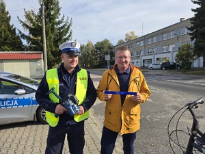 na zdjeciu policjant z rowerzysta który trzyma w ręku odblask otrzymany od policjanta