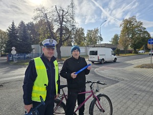 na zdjeciu policjant z rowerzysta który trzyma w ręku odblask otrzymany od policjanta