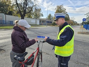 na zdjęciu policjant daje rowerzystce odblask