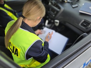 na zdjęciu policjantka wypisuje mandat w radiowozie