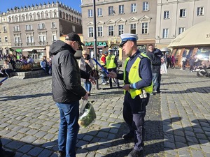 NA ZDJĘCIU POLICJANT ROZDAJE ODBLASKI