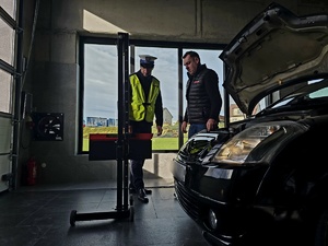 NA ZDJĘCIU DIAGNOSTA I POLICJANT SPRAWDZAJA OSWIETLENIE POJAZDU I USTAWIAJA JE