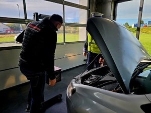 NA ZDJĘCIU DIAGNOSTA I POLICJANT SPRAWDZAJA OSWIETLENIE POJAZDU I USTAWIAJA JE