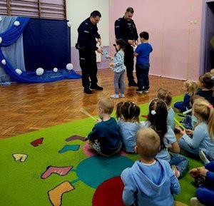 na zdjęciu policjanci przymierzają dzieciom umundurowanie