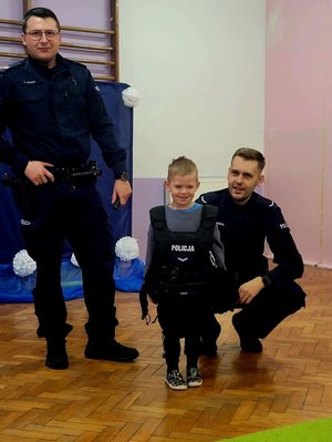 na zdjęciu dzieci przymierzają kamizelki policyjne