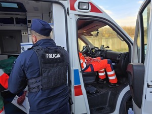 na zdjęciu widać jak policjant pomaga osobom poszkodowanym w wypadku