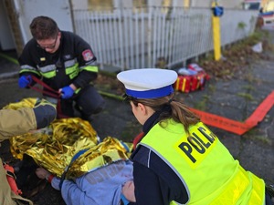 na zdjęciu widać jak policjant pomaga osobom poszkodowanym w wypadku