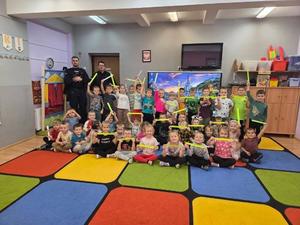 na zdjęciu przedszkolaki z policjantami trzymają odblaski