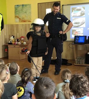 na zdjeciu policjant pokazuje dzieciom wyposazenia