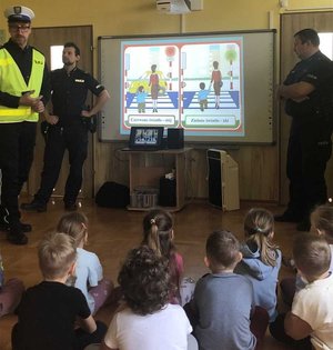na zdjęciu policjant ruchu drogowego opowiada dzieciom o bezpieczeństwie na drodze