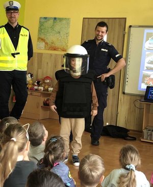 na zdjęciu dziecko ubrane w kask policyjny i kamizelkę