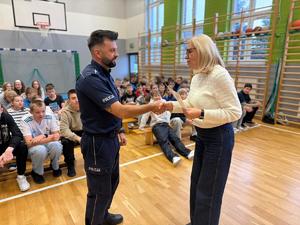 na zdjęciu policjant otrzymuje gratulacje od nauczycielki