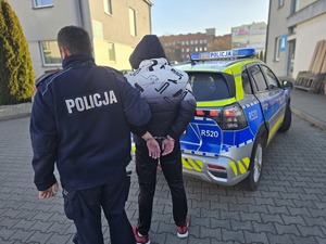 na zdjeciu zatrzymany z policjantem stoją tyłem
