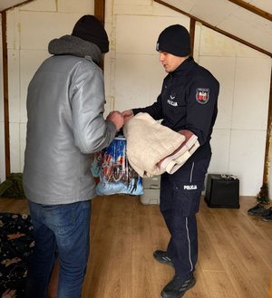 na zdjęciu policjant przekazuje rzeczy mężczyźnie
