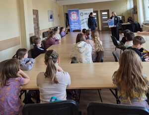 na zdjeciu policjantka pracownik sanepidu i dzieci podczas prelekcji