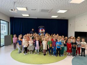 na zdjęciu policjant z przedszkolakami i sznupek