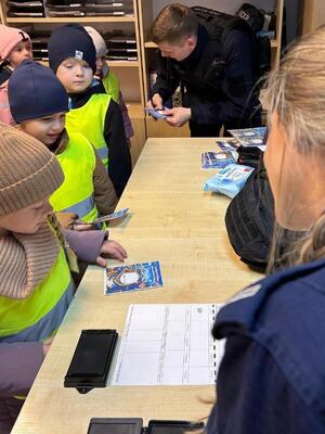 na zdjęciu widzimy dzieci które oglądają komisariat i rozmawiają z policjantami