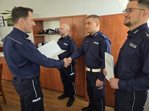 na zdjęciu zastępca komendanta wręczający akty mianowania policjantom