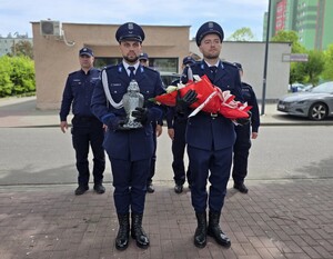 na zdjęciu policjanci przed złożeniem kwiatów oraz zapaleniem znicza